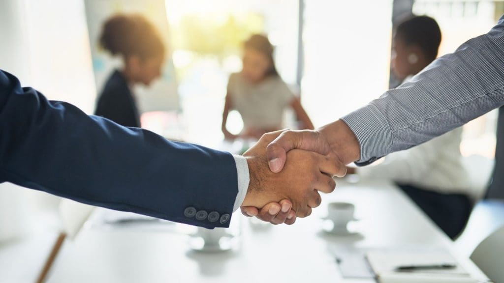 Two people shaking hands over a table.