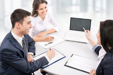 A group of people sitting at a table with laptops.